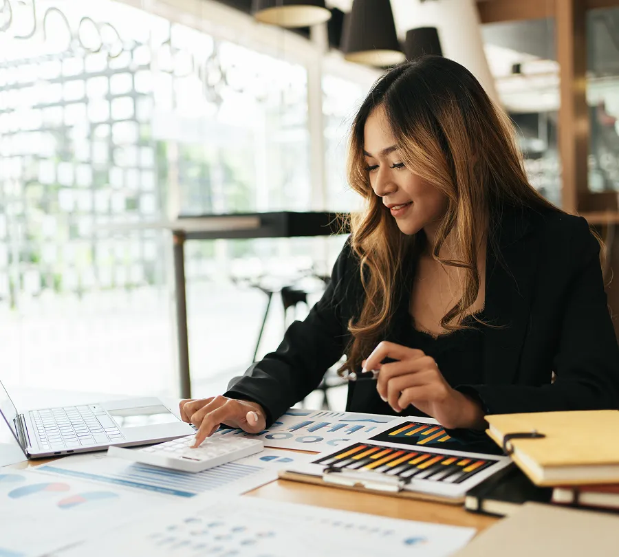 Businesswoman reviewing financial charts and calculations at her desk